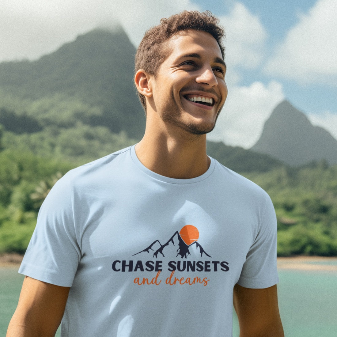 Man wearing a blue nature t-shirt with a mountain and sunset scene and text that says Chase Sunsets and Dreams