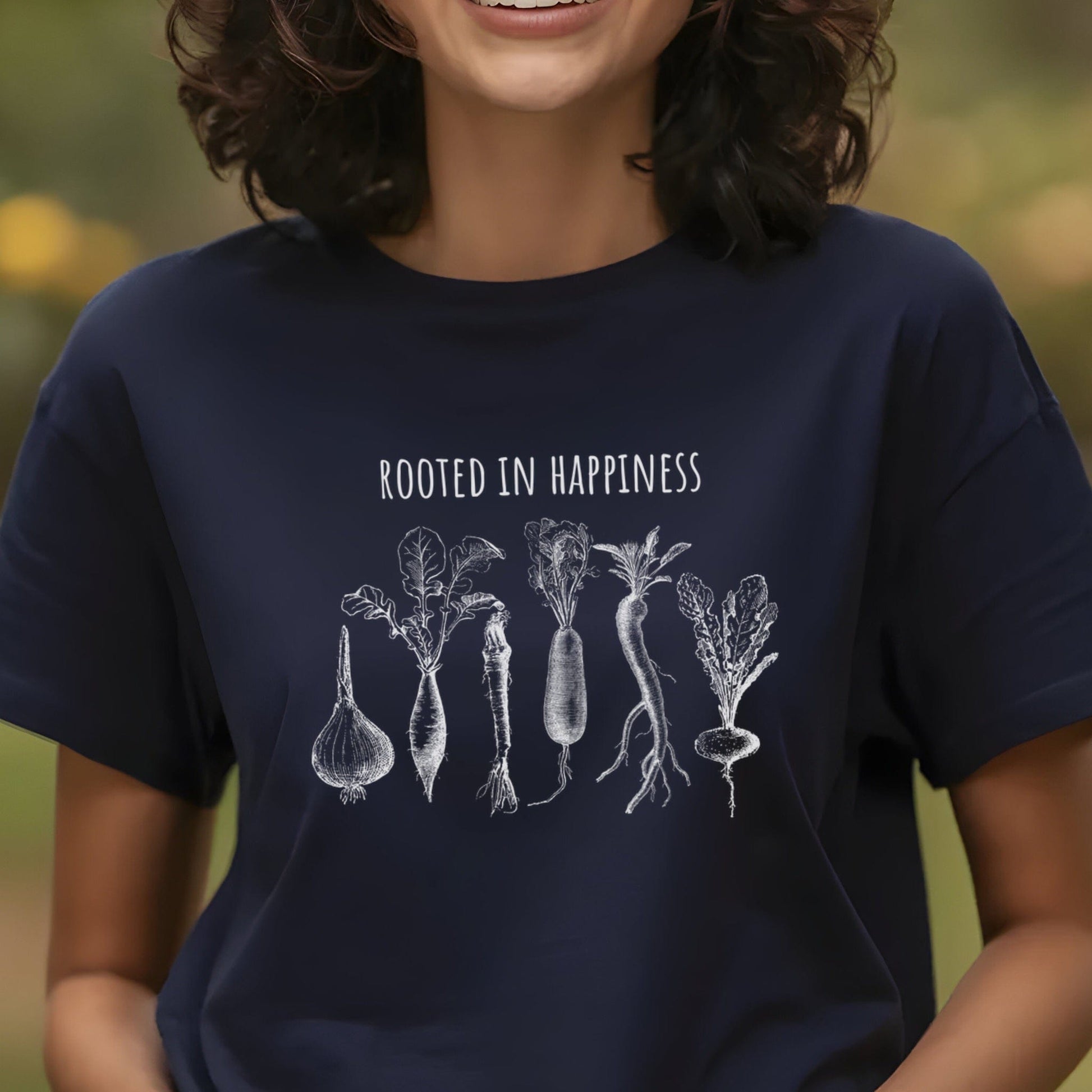 Woman wearing a black gardening tee shirt with vegetables on it and says Rooted in Happiness